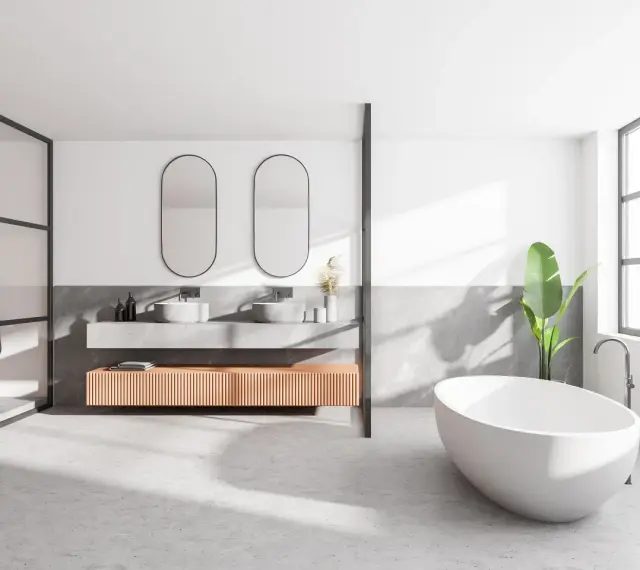 Salle de bain moderne avec baignoire îlot, double vasque et douche. Le sol en béton ciré, un carrelage sans joint, crée une ambiance épurée et contemporaine.