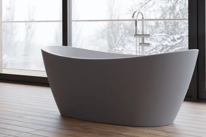 Une baignoire moderne dans une chambre, avec une grande fenêtre offrant une vue sur un paysage enneigé. Parfait pour un moment de détente.