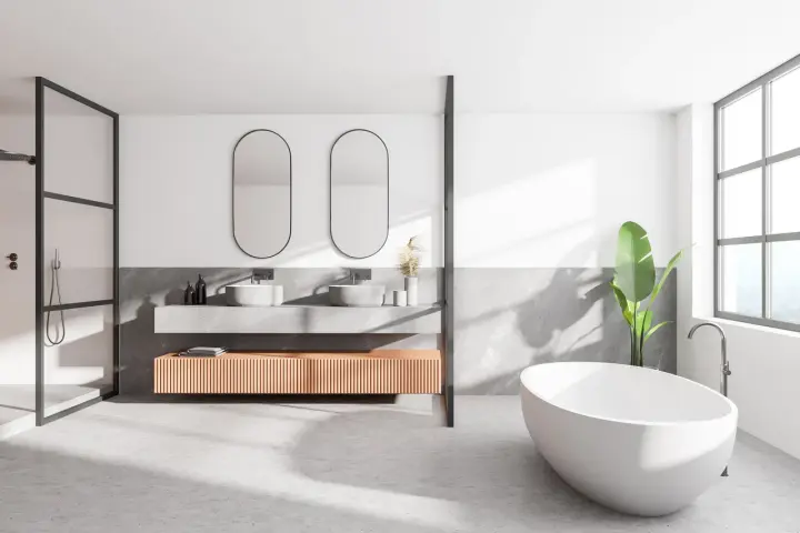 Salle de bain moderne avec baignoire îlot, double vasque et douche. Le sol en béton ciré, un carrelage sans joint, crée une ambiance épurée et contemporaine.