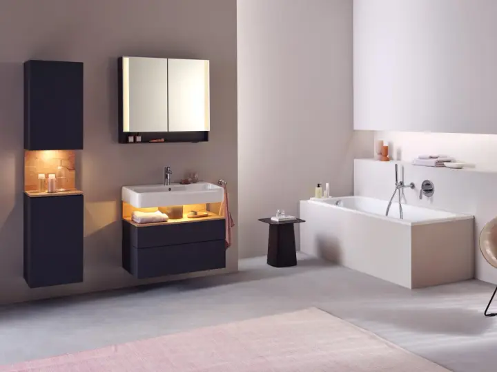 Salle de bain moderne avec baignoire, lavabo et meubles suspendus. Le sol en béton poli et le carrelage mural clair facilitent le nettoyage.