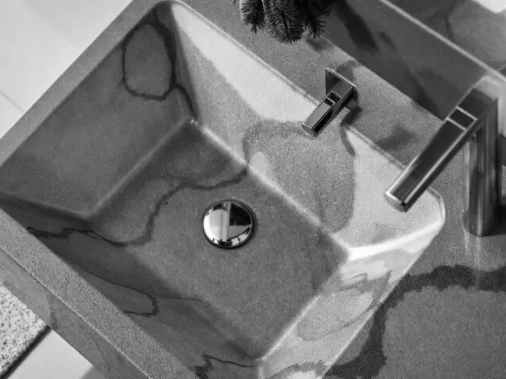 Évier en béton gris avec des veines sombres, robinetterie moderne. La différence évier lavabo est subtile, mais ici, c'est un lavabo design.