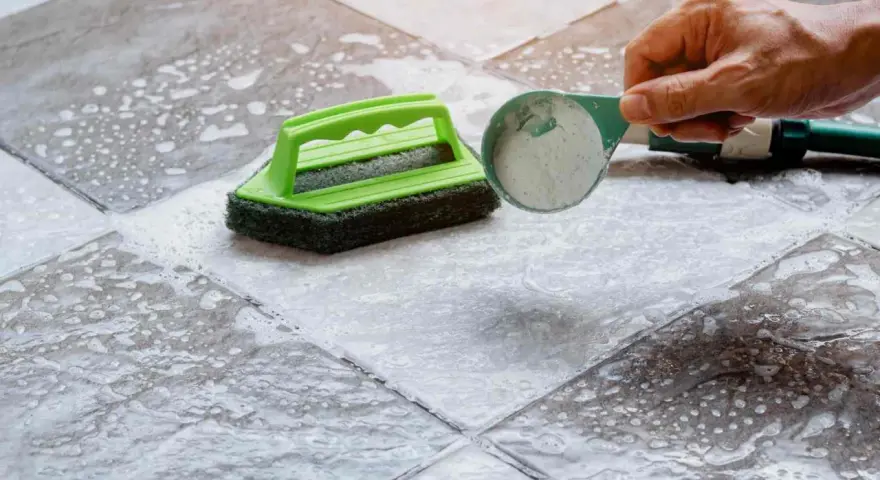 Nettoyer un carrelage mat et poreux avec une brosse et une poudre nettoyante.