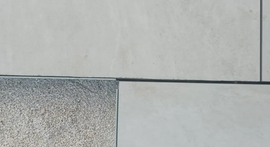 Détail d'un sol extérieur avec des dalles claires et une zone de gravier, montrant la précision du couper carrelage.
