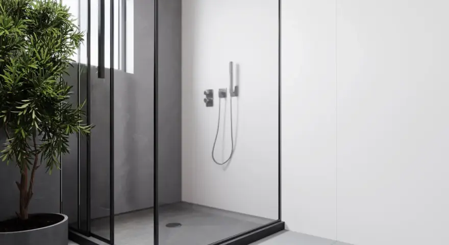Douche surélevée pour évacuation, avec une paroi en verre et un robinet moderne. Un arbre vert apporte une touche de nature.