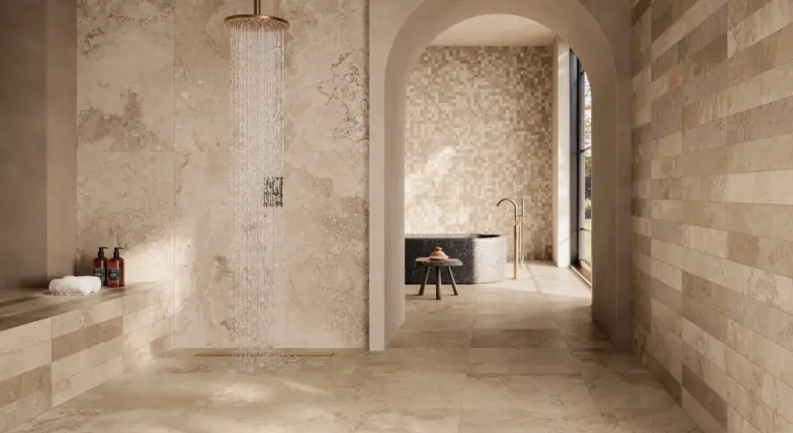 Douche moderne avec carrelage effet pierre naturelle. Quel carrelage pour salle de bain ? Ce choix de tons chauds et de textures variées crée une ambiance zen et luxueuse.