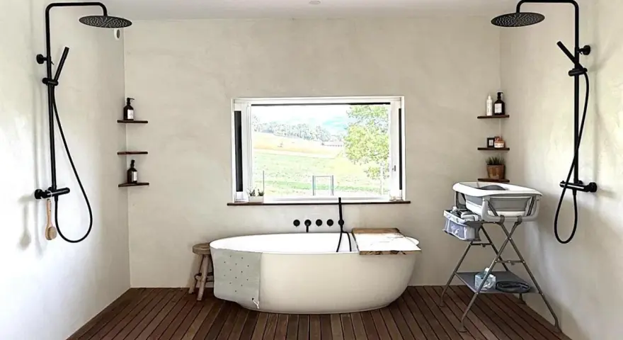 Une **salle de bain intemporelle** avec baignoire îlot, deux douches murales, et une vue sur la campagne.