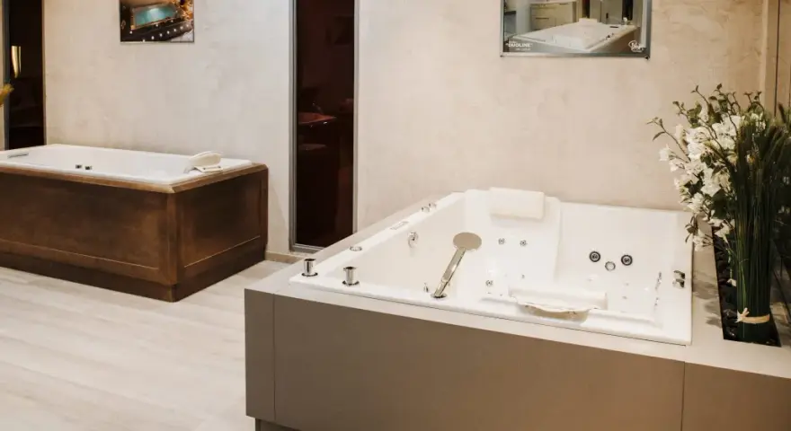 Deux baignoires modernes, une habillée de bois, l'autre d'un revêtement gris, illustrent comment habiller une baignoire avec style.
