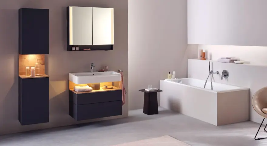 Salle de bain moderne avec baignoire, lavabo et meubles suspendus. Le sol en béton poli et le carrelage mural clair facilitent le nettoyage.