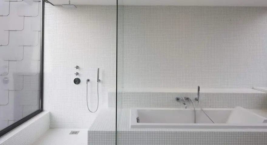 Salle de bain moderne avec douche à l'italienne et baignoire îlot, le tout revêtu de petites mosaïques blanches.
