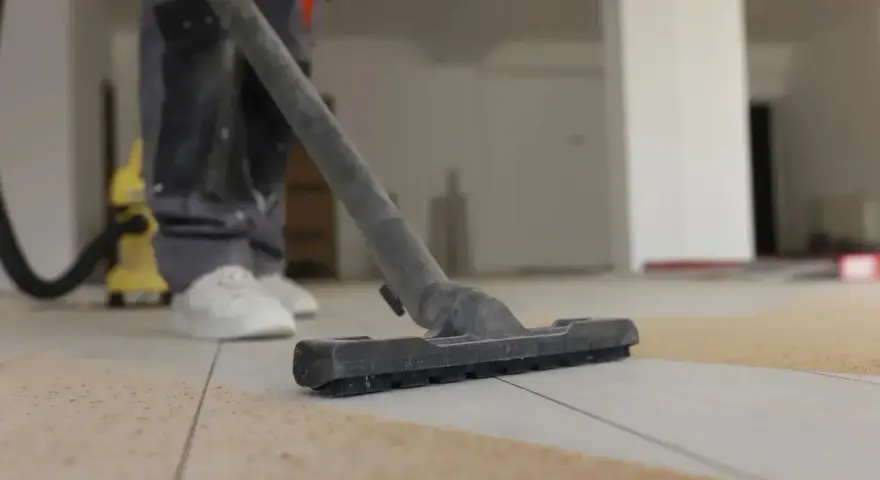Nettoyage de carrelage après chantier : un aspirateur passe sur le sol poussiéreux.