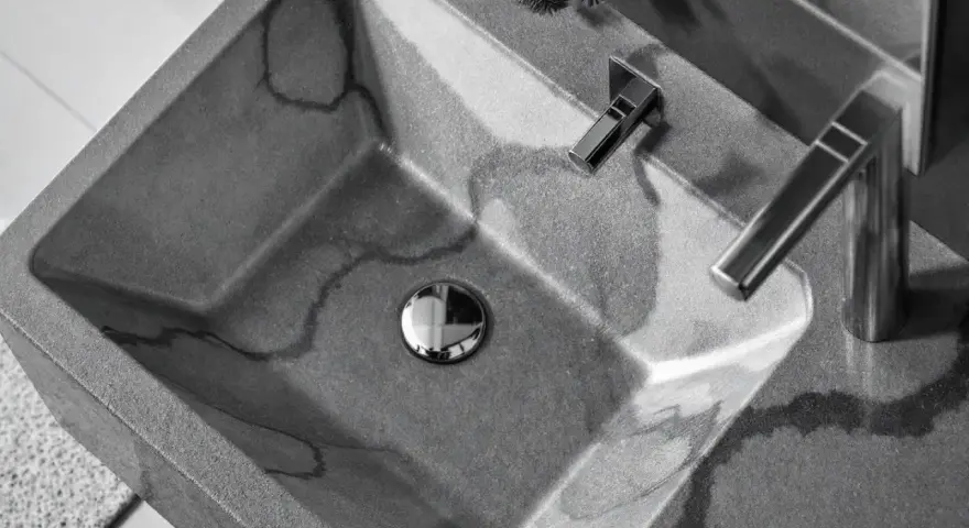 Évier en béton gris avec des veines sombres, robinetterie moderne. La différence évier lavabo est subtile, mais ici, c'est un lavabo design.