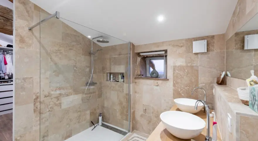 Salle de bain moderne avec une belle installation douche, deux lavabos et un dressing ouvert.
