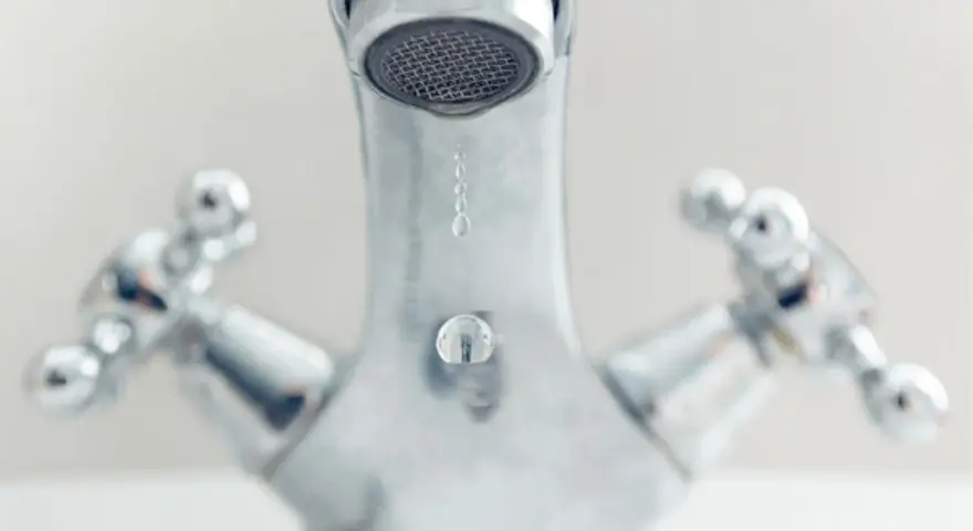 Gouttes d'eau tombant d'un robinet chromé. Comprendre la différence entre mitigeur et mélangeur pour une meilleure gestion de l'eau.