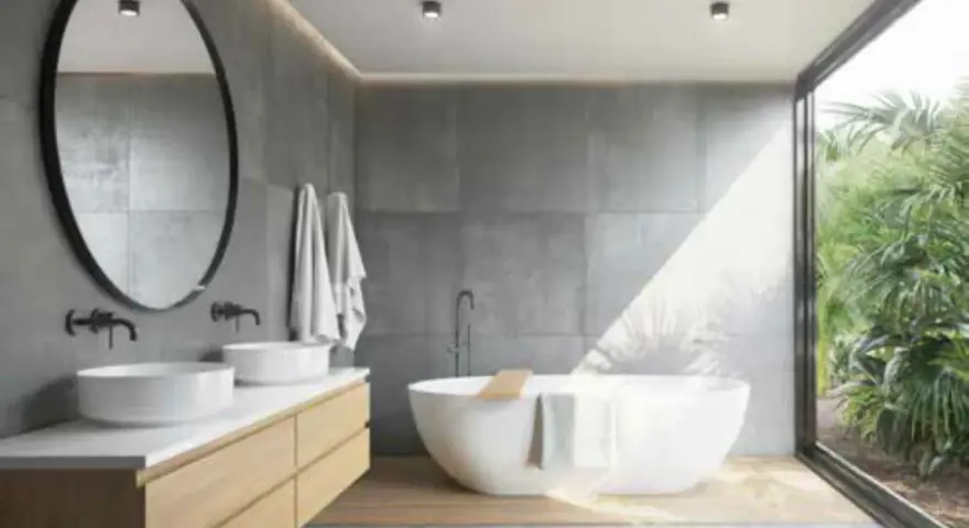 Salle de bain moderne avec baignoire îlot, double vasque et grande fenêtre donnant sur la végétation. L'étanchéité entre bac à douche et mur est assurée par des joints discrets.