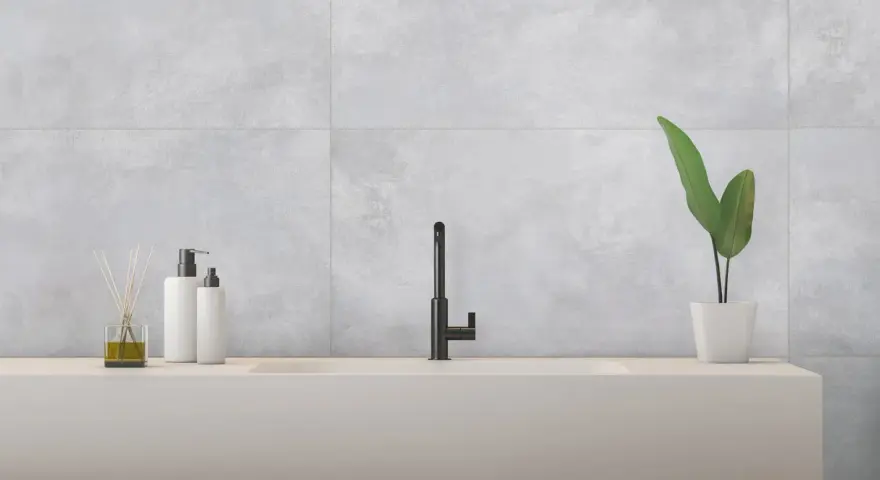 Évier moderne avec robinetterie noire, flacons de savon et plante verte, sur un mur en carrelage rectifié gris.