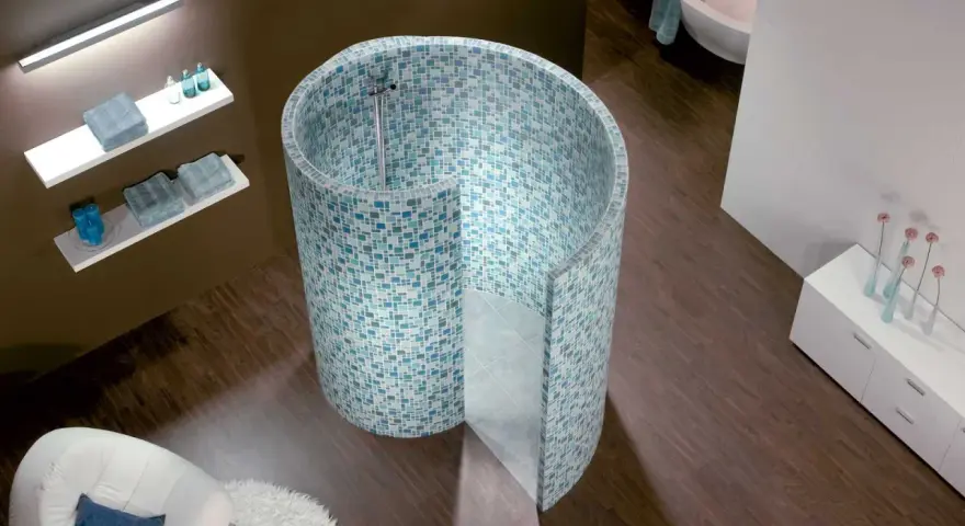Une douche escargot aux mosaïques bleues et vertes, avec une baignoire et un fauteuil dans une salle de bain moderne.