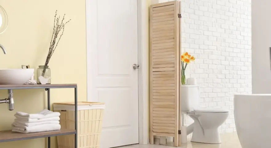 Un paravent en bois crée une séparation toilette salle de bain, cachant le WC derrière une porte blanche.