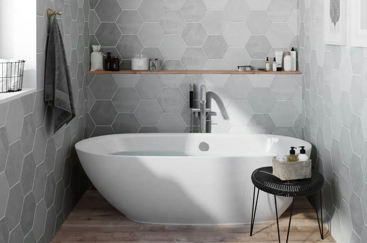 Salle de bain moderne avec baignoire îlot, mur en pose carrelage hexagonal gris et étagère en bois.