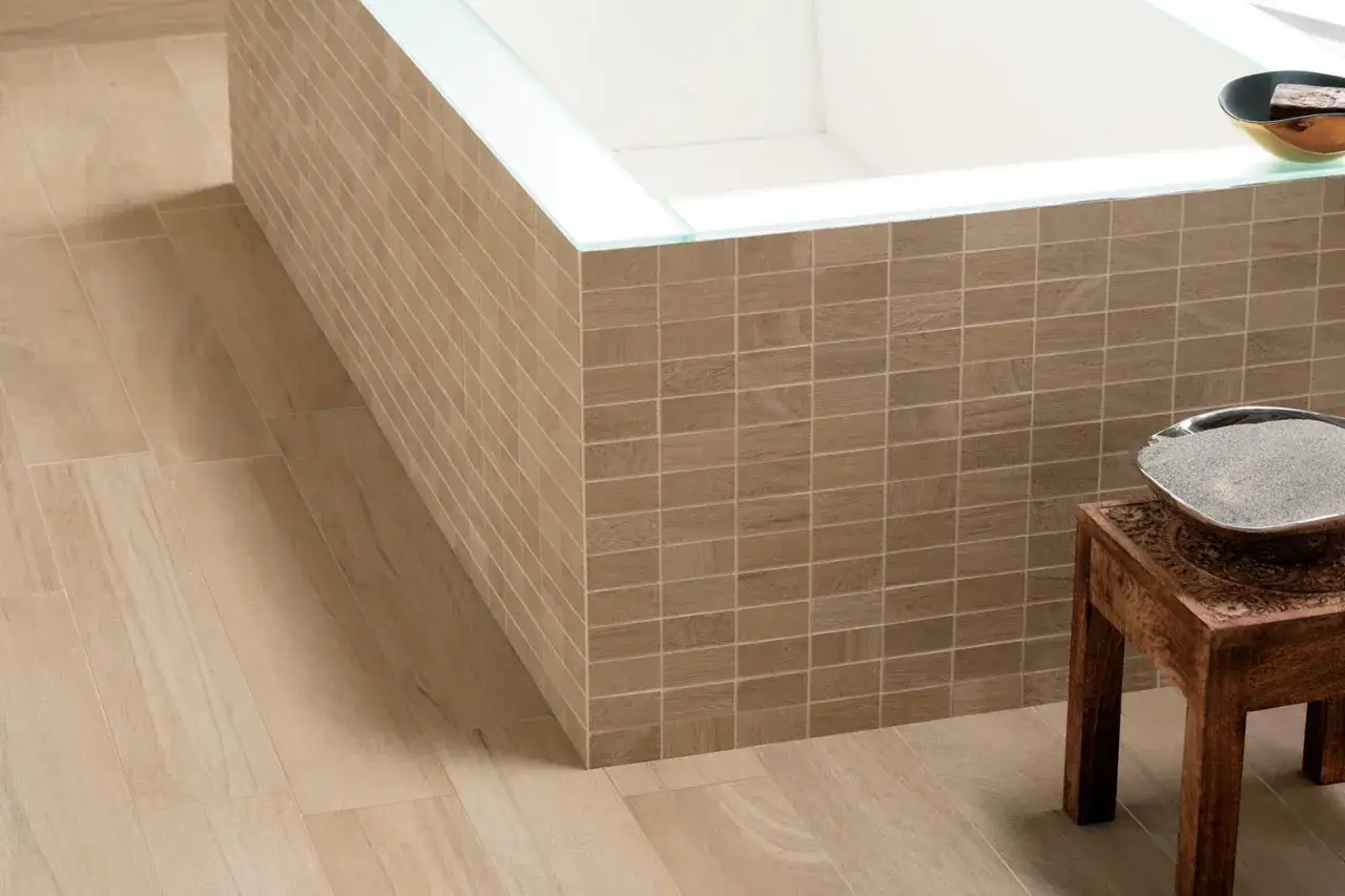 Salle de bain avec carrelage imitation bois au sol et mosaïque sur le muret de la baignoire. L'épaisseur du joint carrelage 60x60 est discrète.