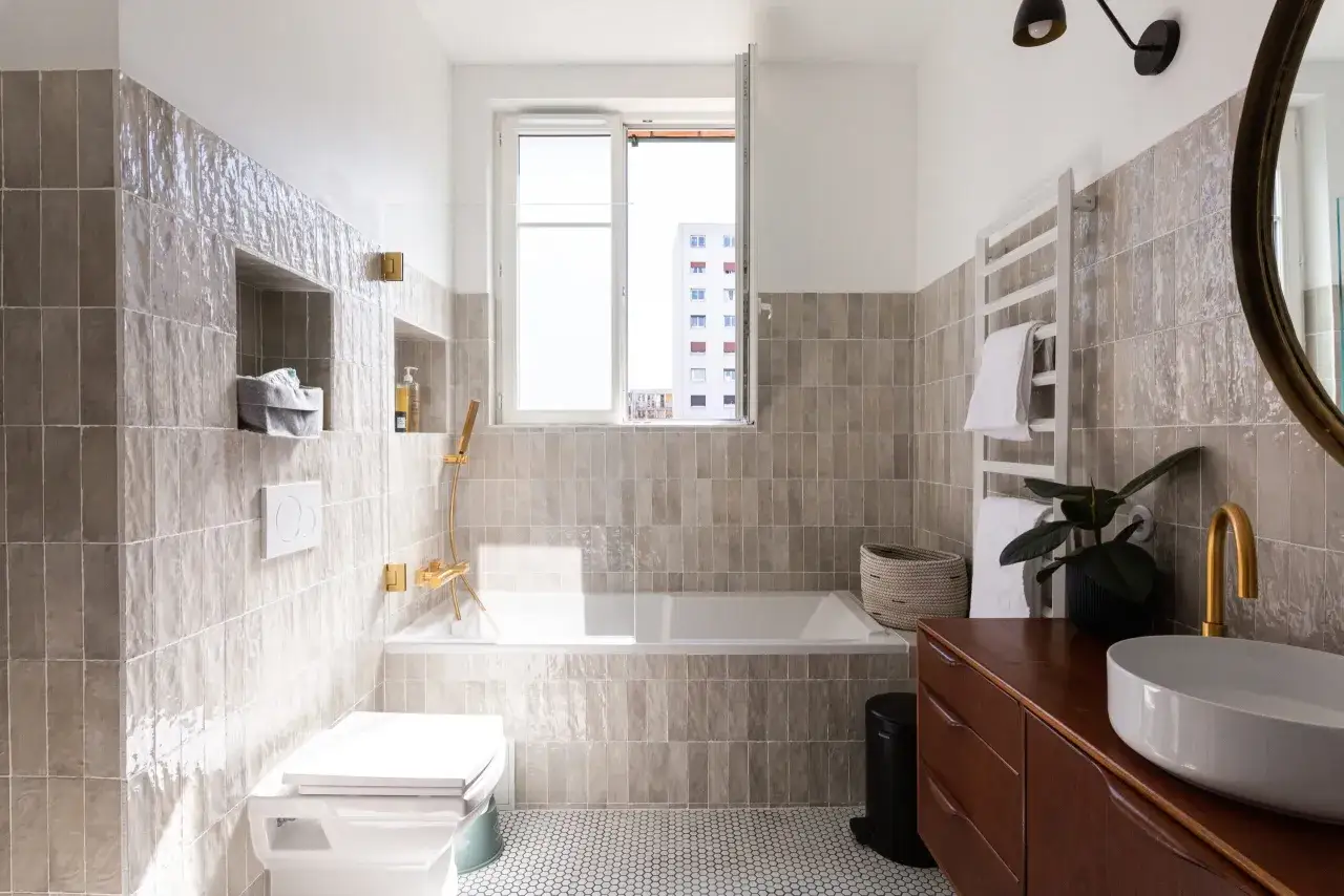Salle de bain moderne avec carrelage zellige gris, baignoire, WC suspendu et vasque sur meuble en bois. Inspiration zellige pour une ambiance zen.