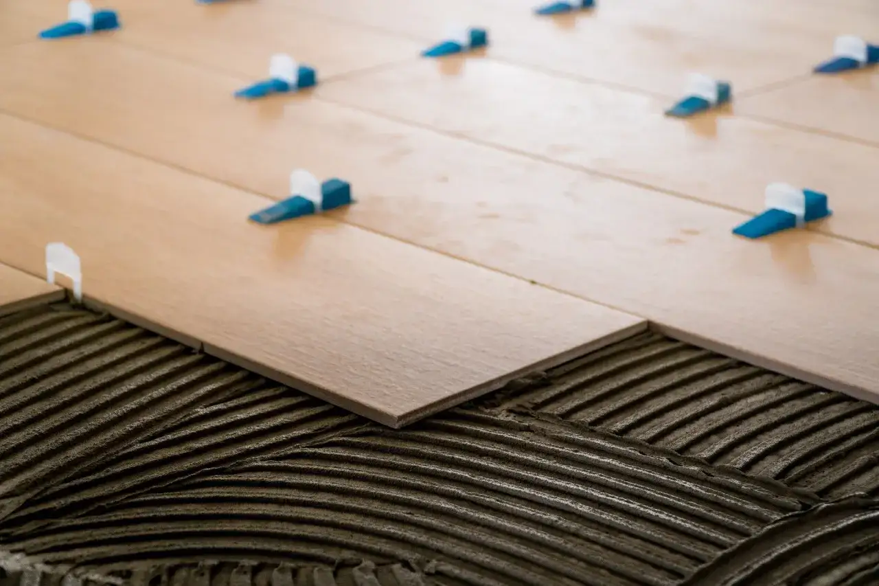 Pose de carrelage au sol 30x60, avec des croisillons bleus et blancs pour assurer une largeur de joint parfaite.