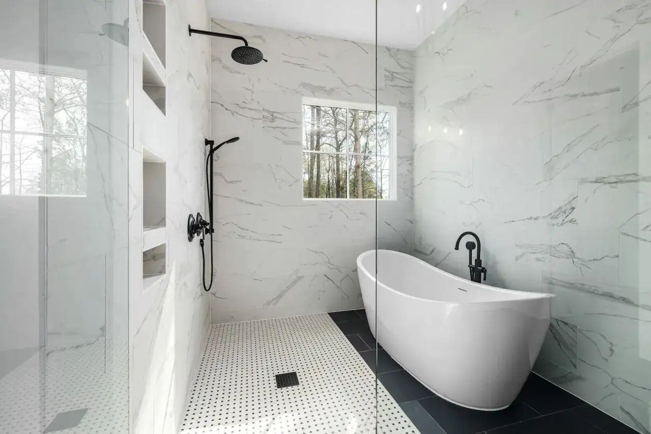 Salle de bain moderne avec baignoire îlot et douche séparée, le tout habillé de carrelage effet marbre blanc et noir.