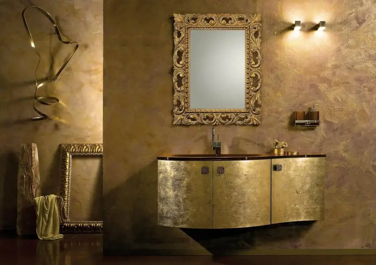 Salle de bain luxueuse avec un meuble-lavabo et un miroir orn&eacute;s, le tout baign&eacute; d'une lumi&egrave;re dor&eacute;e.