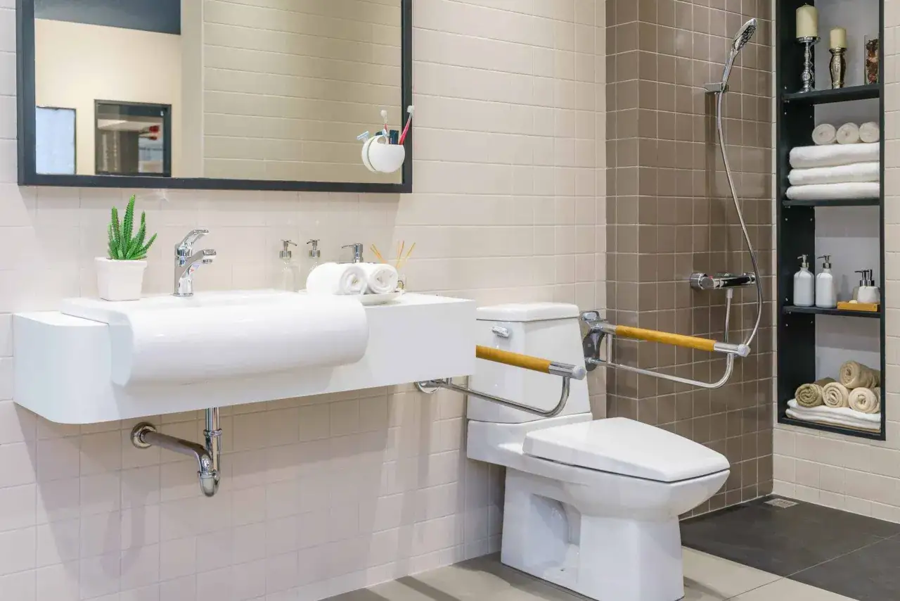 Salle de bain moderne avec lavabo PMR norme, toilettes avec barres d'appui et douche.