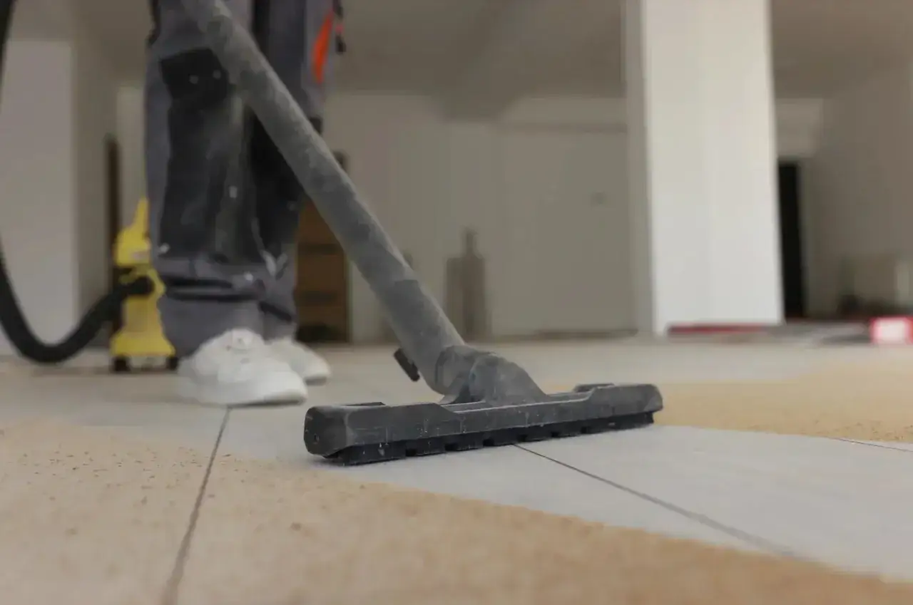 Nettoyage de carrelage après chantier : un aspirateur passe sur le sol poussiéreux.