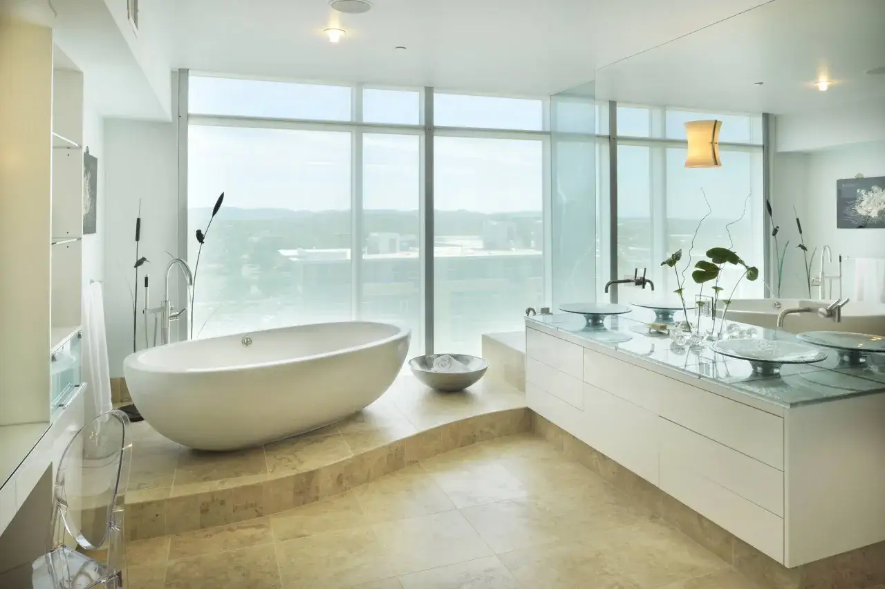 Une baignoire sur une estrade dans une salle de bain moderne avec de grandes fenêtres offrant une vue panoramique.