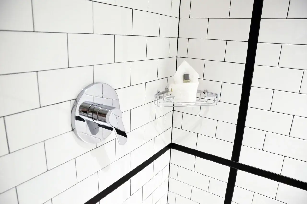 Coin de douche moderne avec robinetterie chromée et étagère contenant des serviettes. Le nettoyage carrelage est facilité par ces surfaces brillantes.