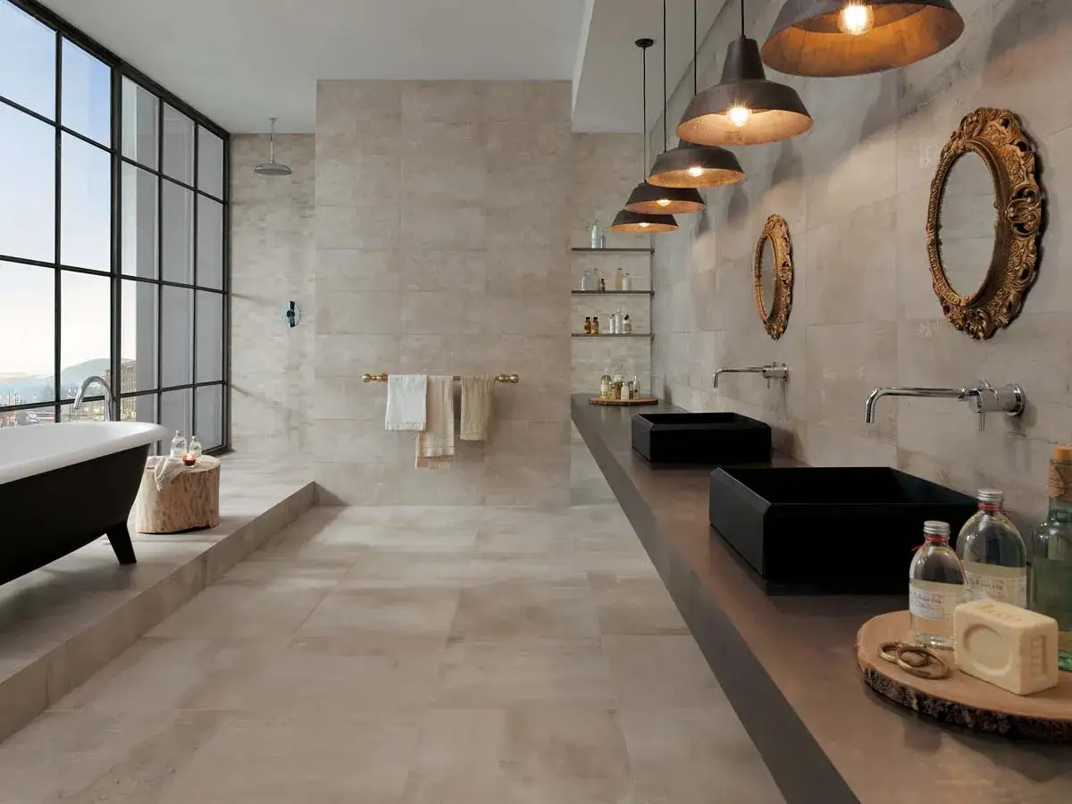 Élégante salle de bain industrielle avec baignoire îlot, deux lavabos noirs et de grandes fenêtres offrant une vue panoramique.