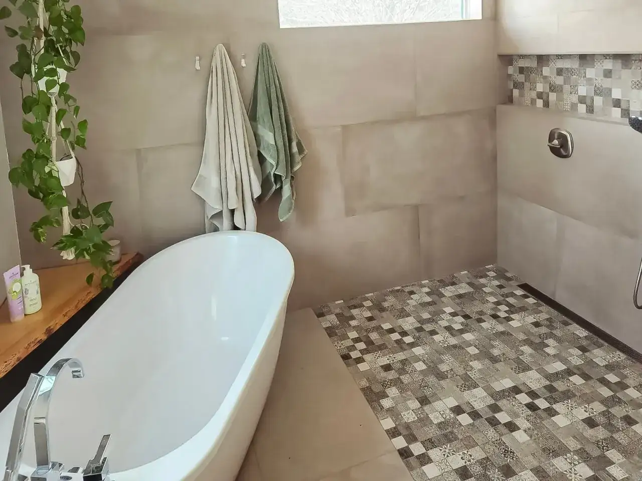 Salle de bain moderne en cours de construction, avec baignoire îlot, carrelage au sol et mur de douche décoratif.
