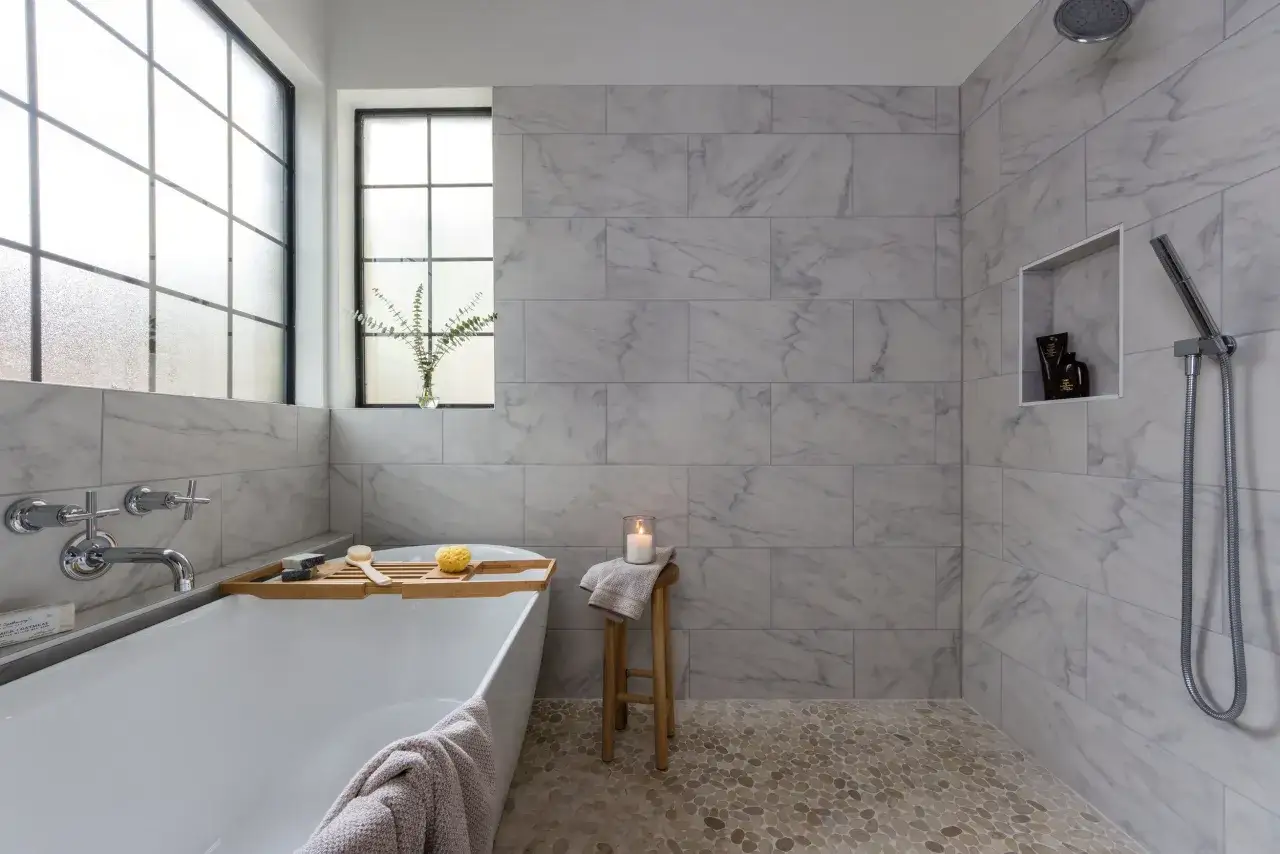 Salle de bain moderne avec baignoire, douche et carrelage 60x120 pose d&eacute;cal&eacute;e. Sol en galets.