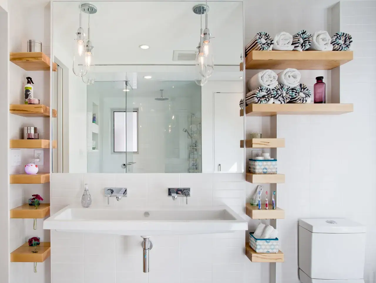Étagères en bois flotté pour une idée rangement salle de bain moderne. Serviettes roulées, produits de beauté et accessoires organisés.