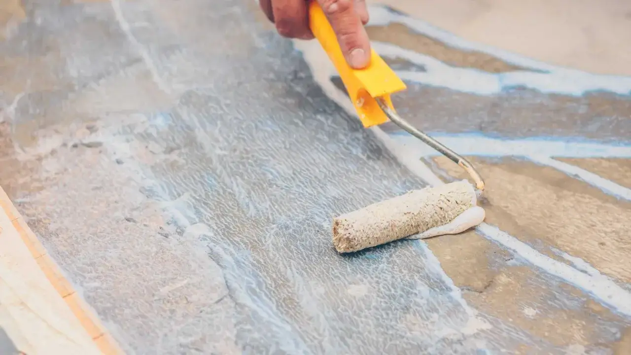 Application d'une sous couche carrelage au rouleau sur un sol.