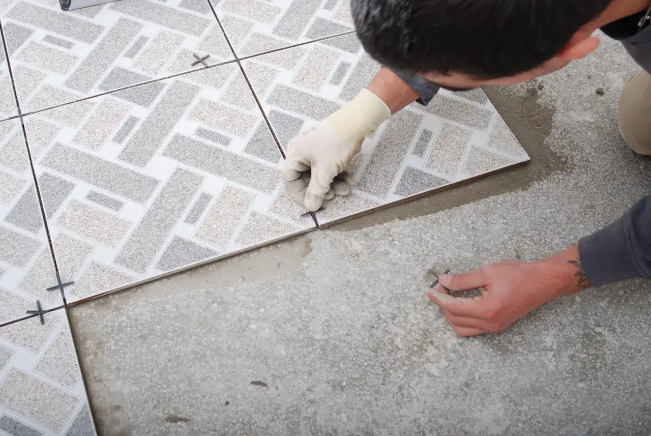 Pose d'un carrelage aux motifs géométriques. Un carreleur ajuste une nouvelle pièce, préparant la pose pour une décennale carrelage impeccable.