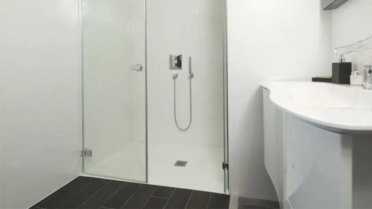Salle de bain moderne avec douche à l'italienne et lavabo incurvé. Le sol de la douche est un ragréage sur carrelage, offrant une surface lisse et uniforme.