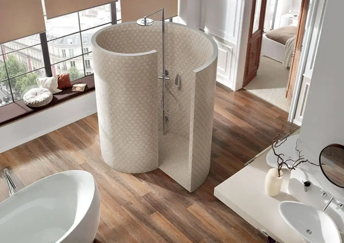 Douche atypique cylindrique en mosa&iuml;que, avec baignoire et lavabo dans une salle de bain moderne.