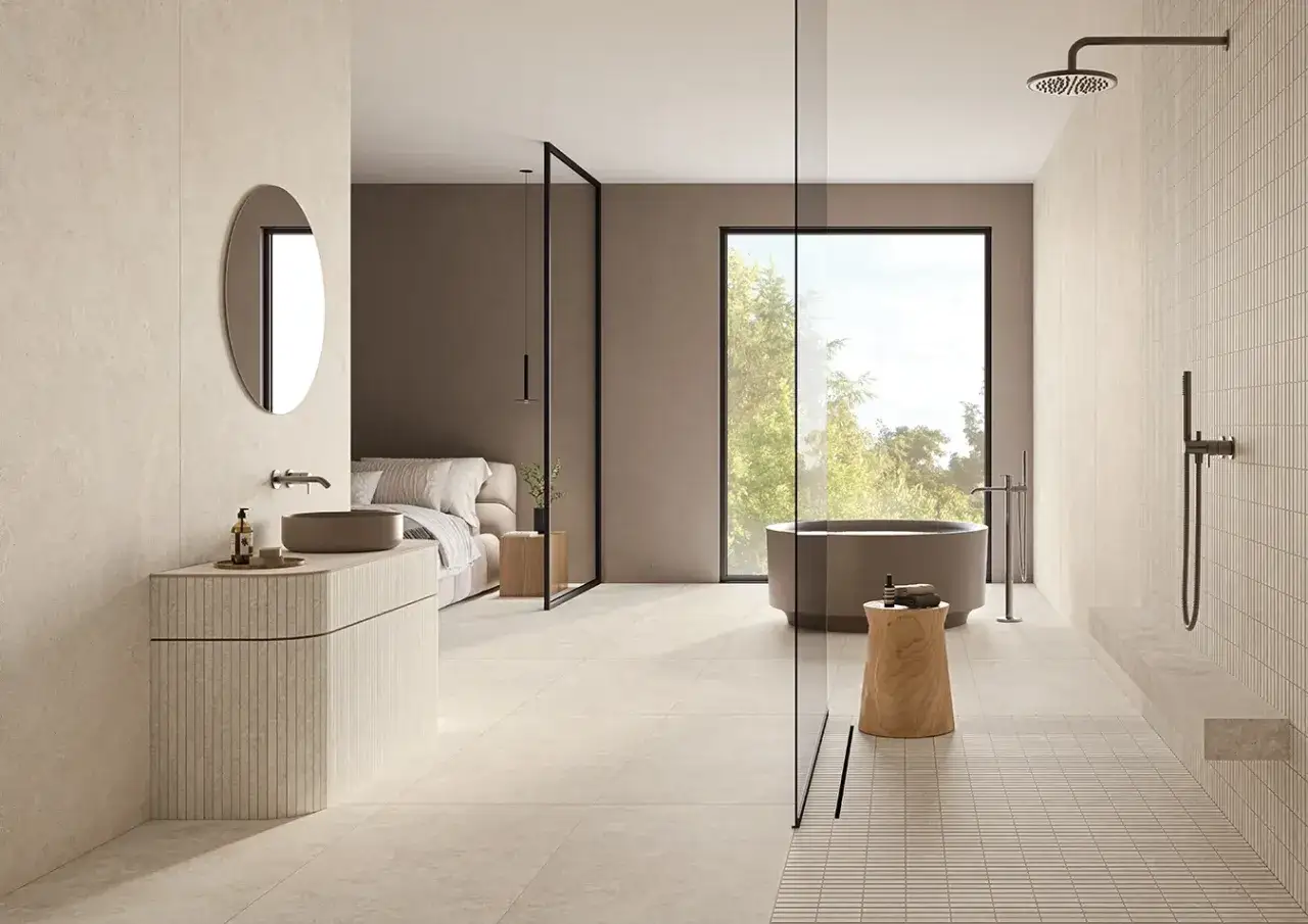 Salle de bain moderne avec baignoire, douche, lavabo et lit. Le sol et les murs sont recouverts de grès cérame émaillé aux tons clairs.