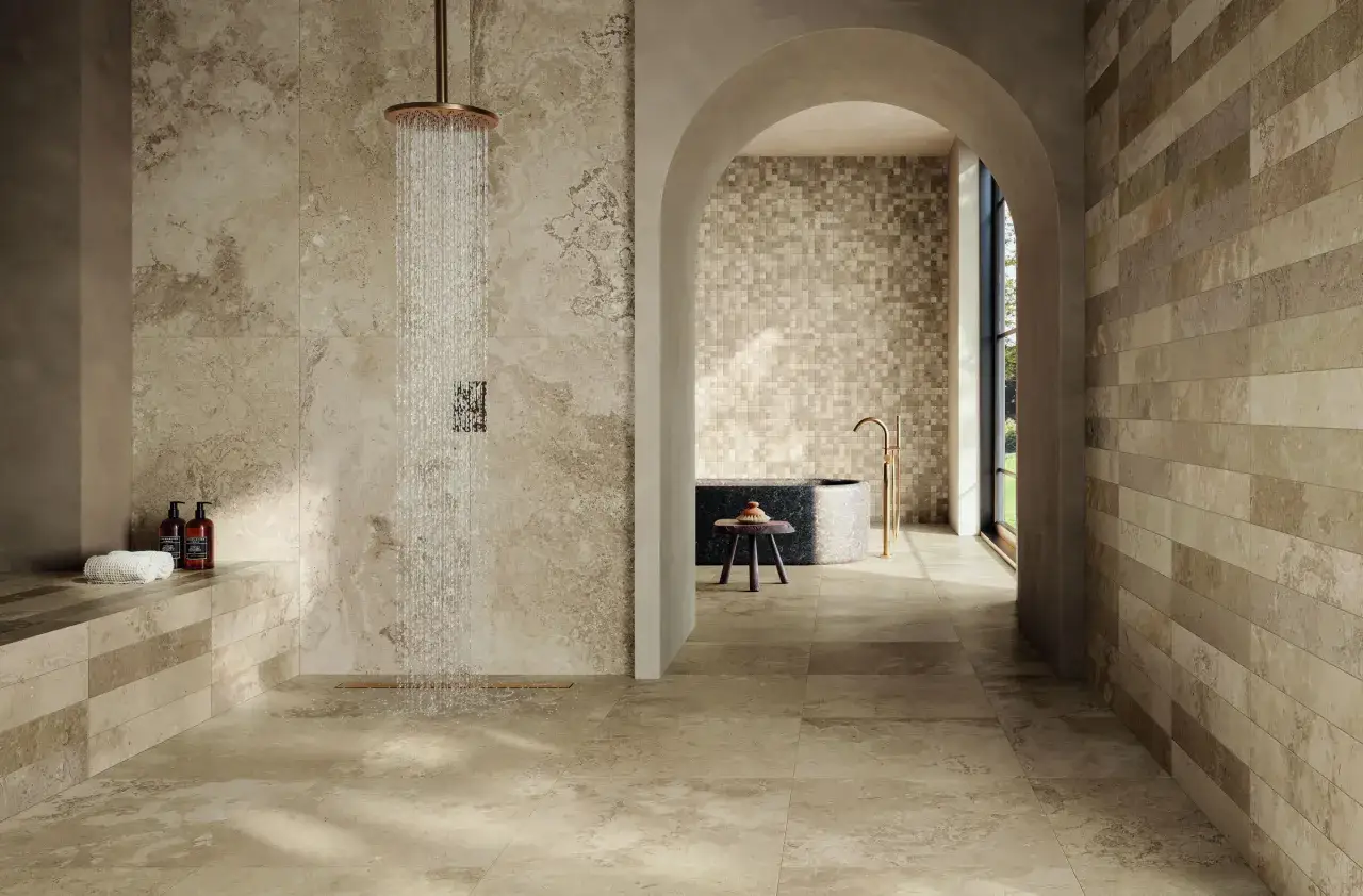 Salle de bain luxueuse avec douche à l'italienne. Le choix du carrelage, en travertin et mosaïque, crée une ambiance naturelle et apaisante.